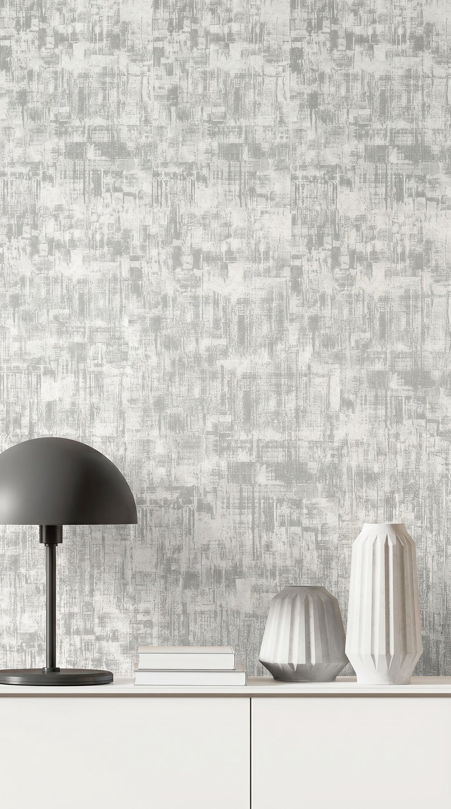 A modern lamp, books, and two textured vases sit on a white cabinet against Distressed Faux Wallpaper.