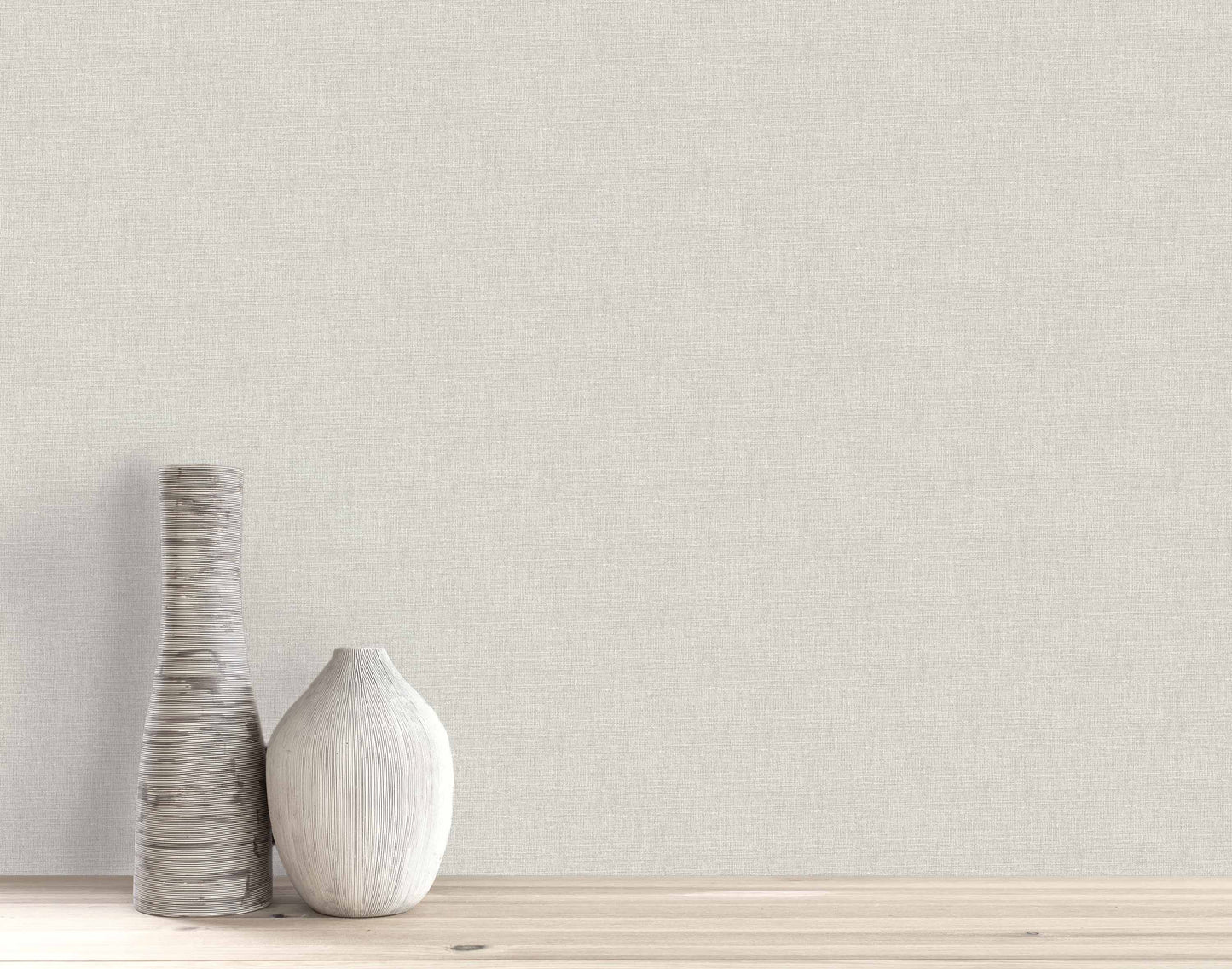 Two white ceramic vases on wood with a plain, light beige Woven Linen Effect Wallpaper background.