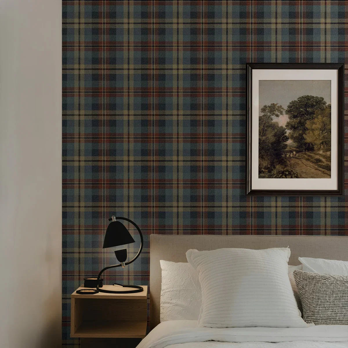 A cozy bedroom with Tailored Plaid Peel Stick wallpaper, a landscape painting, white pillows, and a black lamp.
