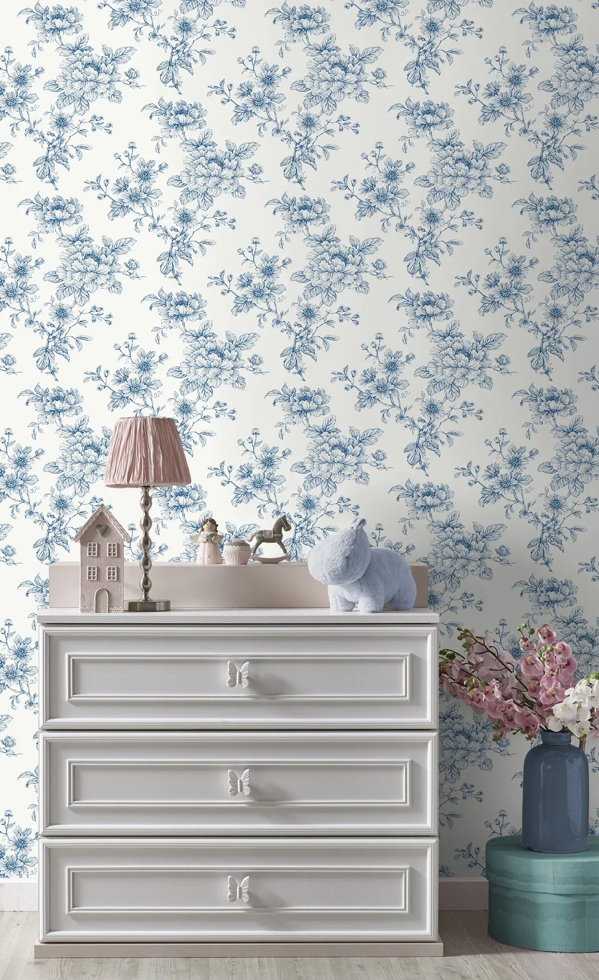 White dresser with lamp, toy house, plush hippo, and flowers against Cherished Rose Peel Stick wallpaper.