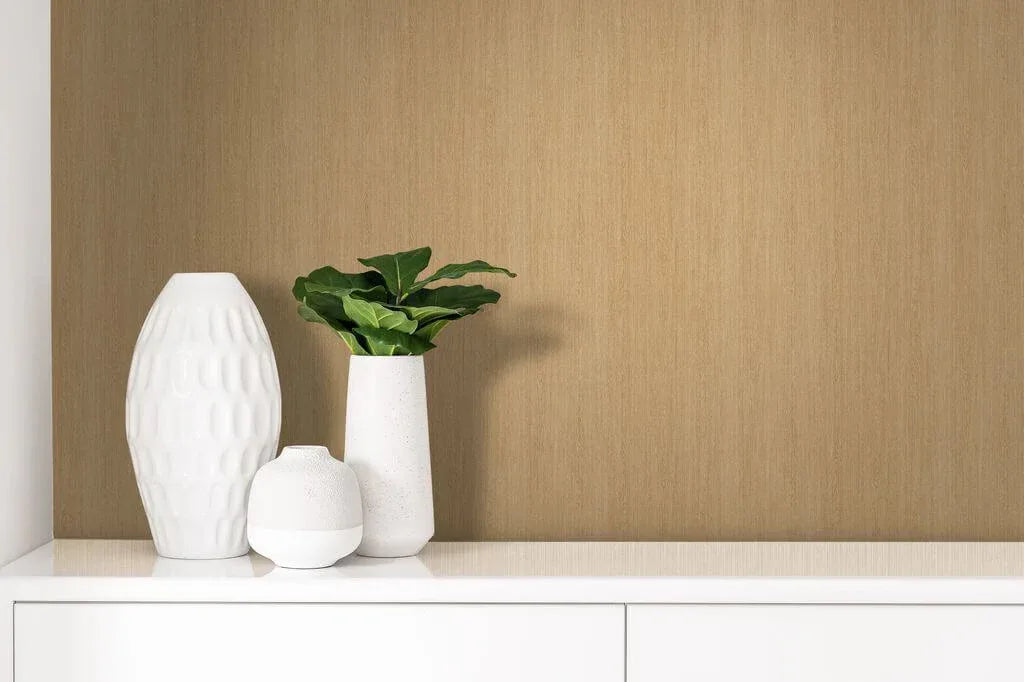 Three white vases, one with a green plant, sit on a cabinet against a Wood Plains Wallpaper feature wall.