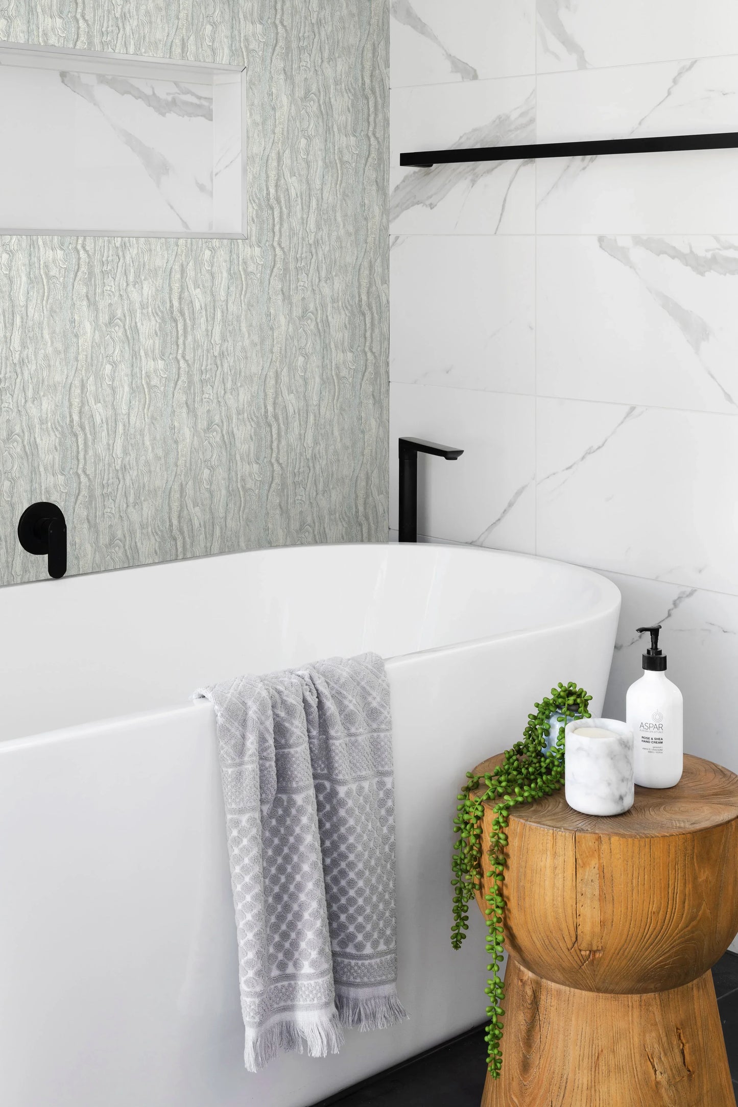 Modern bathroom with a white tub, gray towel, plant, and Marble Texture Wallpaper for an easy DIY makeover.