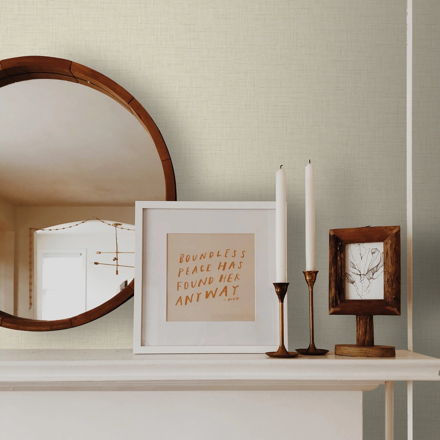 White shelf with two candles and two picture frames against a wall decorated with Beige Linen Texture Commercial & Vinyl.