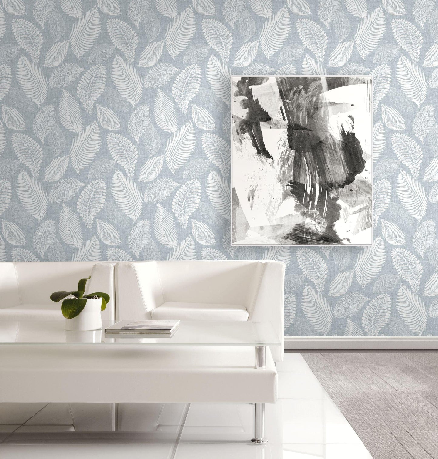 Modern living room with light blue leaf-patterned wallpaper Scattered Leaves Wallpaper - Casa Mia Wallcovering, white sofa, and abstract art.