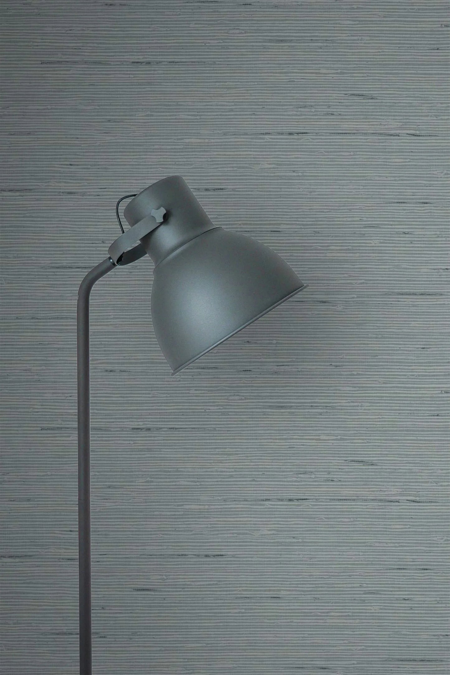 A gray metal floor lamp with a dome shade stands against Natural Weave Commercial Vinyl wallpaper.