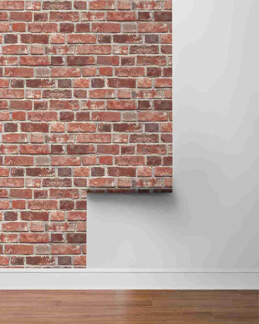 A white wall with Brick Peel Stick limestone wallpaper partially covering it, above a wooden floor.