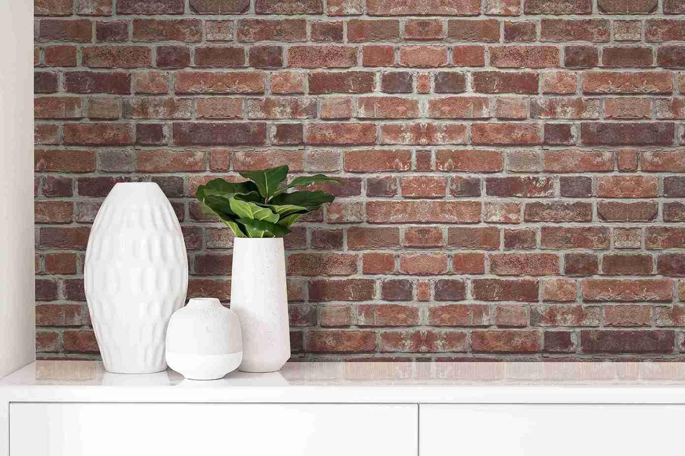Three white vases and a green plant on a cabinet, set against Brick Peel Stick wallpaper.