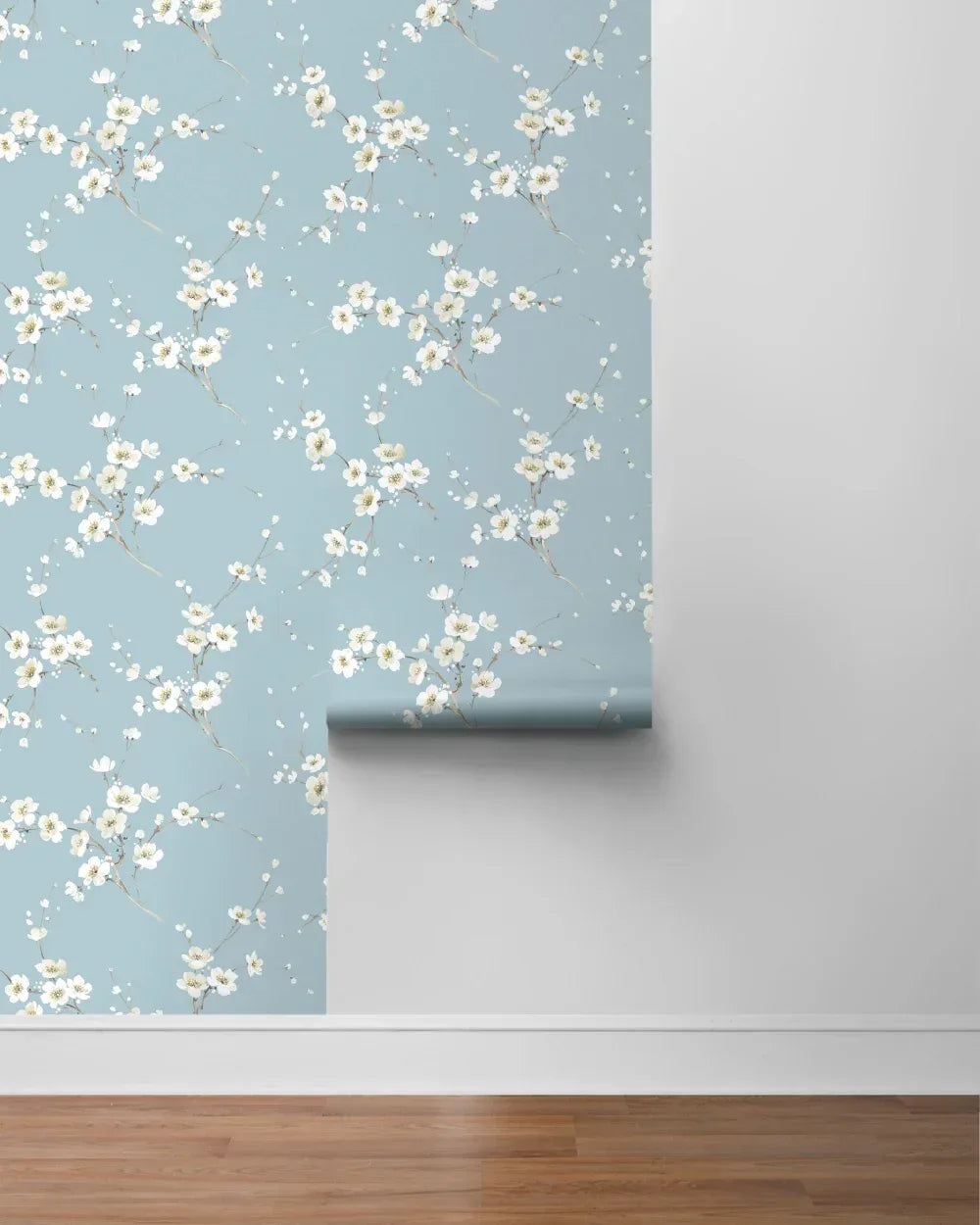 Cherry Blossoms Peel Stick wallpaper with a white floral pattern is partially applied above a wooden floor.