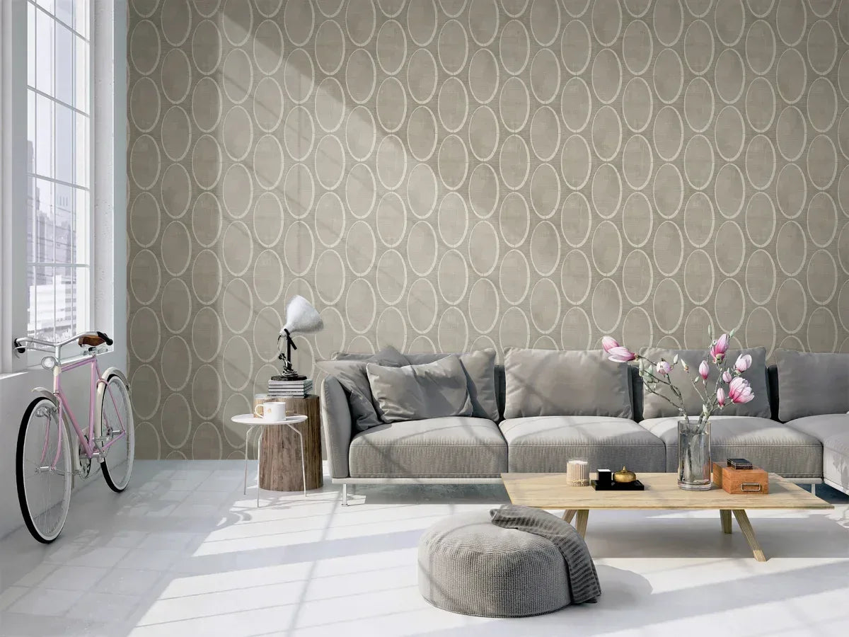 Modern living room with a gray sectional, round coffee table, pouf, bike, and Circles Wallpaper.
