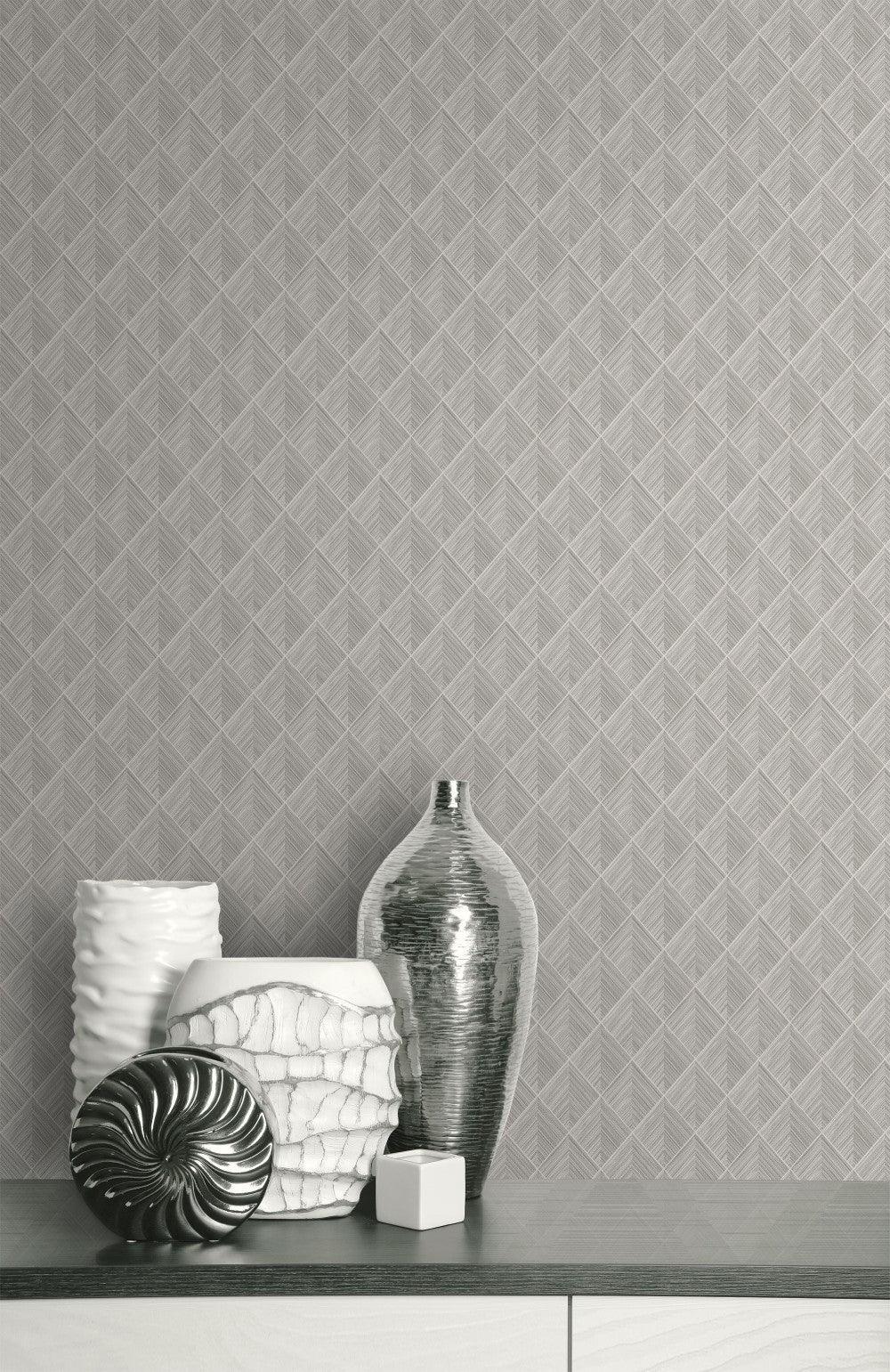 Silver and white vases sit on a modern surface against Pyramid Grasscloth Wallpaper with geometric wall decor.