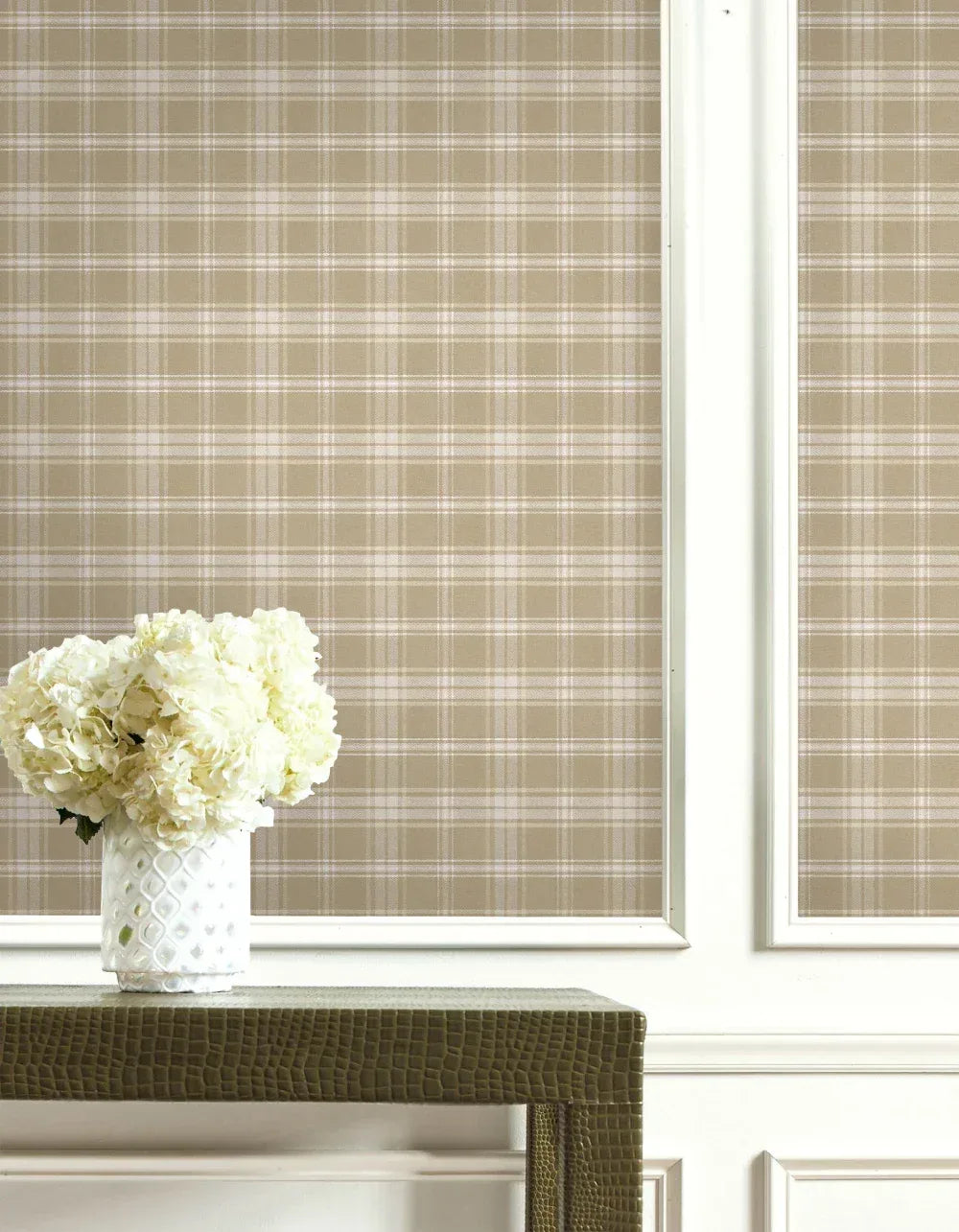 White flowers in a textured vase on a green table, set against Tartan Wallpaper with white trim.