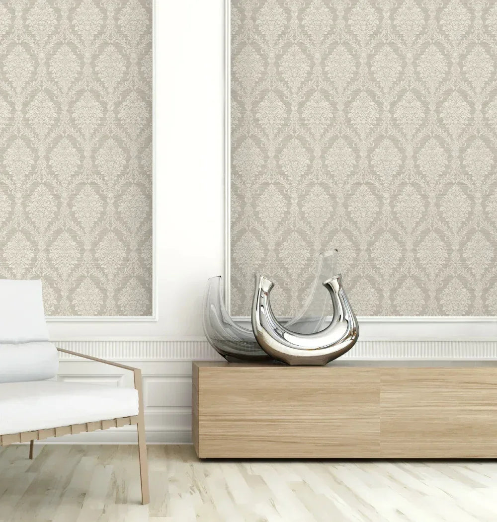 Modern living room with Damask Cameo Wallpaper, a wooden console, abstract glass decor, and a white chair on light wood floors.