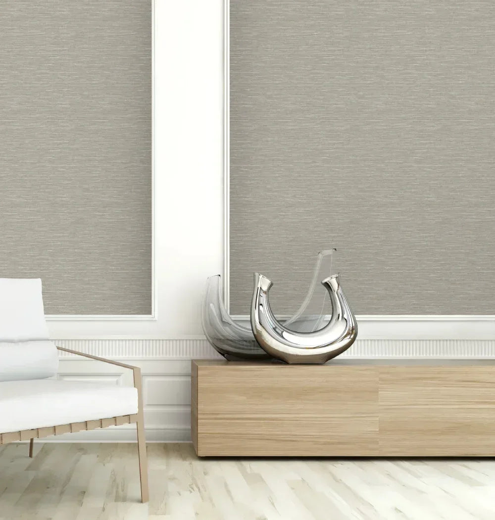 Modern minimalist room with a white chair, wood cabinet, and Soft Fabric Wallpaper behind decorative glass vases.