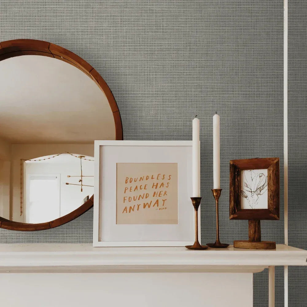 Round mirror, framed art, and candles on a white mantel with Modern Fabric Wallpaper as a stylish backdrop.