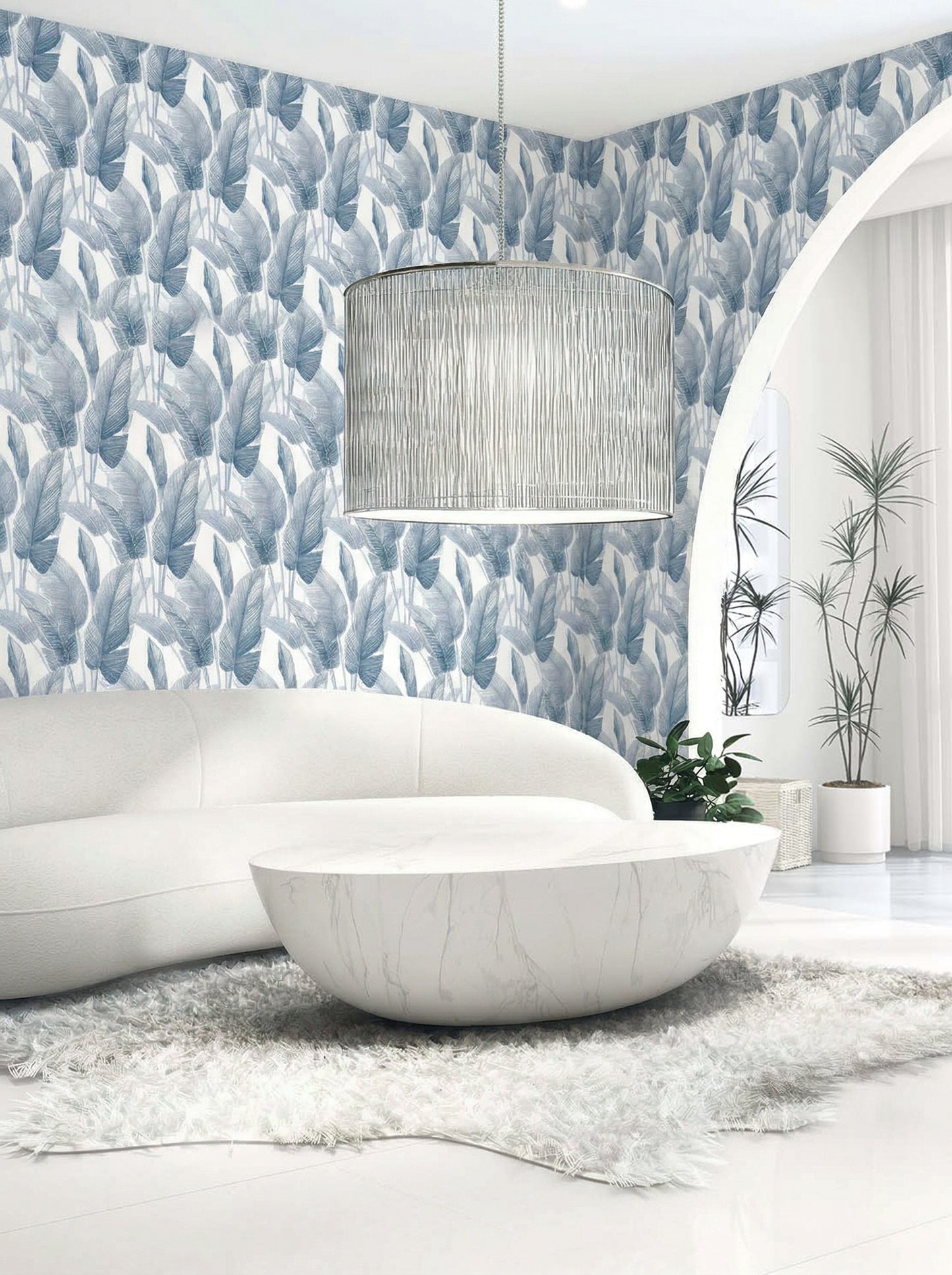Modern living room with a white curved sofa, round coffee table, and blue Lace Leaf Wallpaper behind a pendant light.