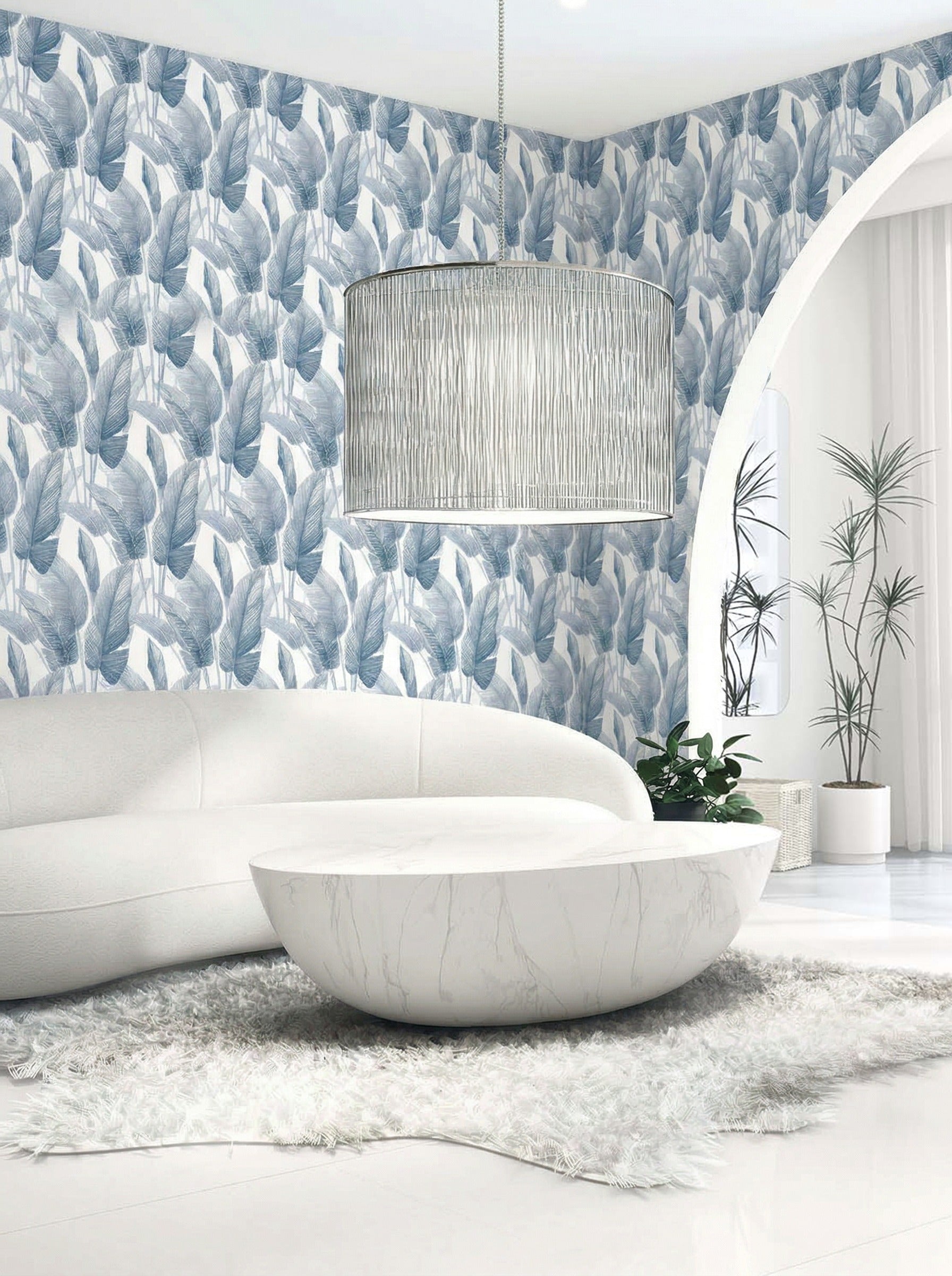 Modern living room with a white curved sofa, round coffee table, and blue Lace Leaf Wallpaper behind a pendant light.
