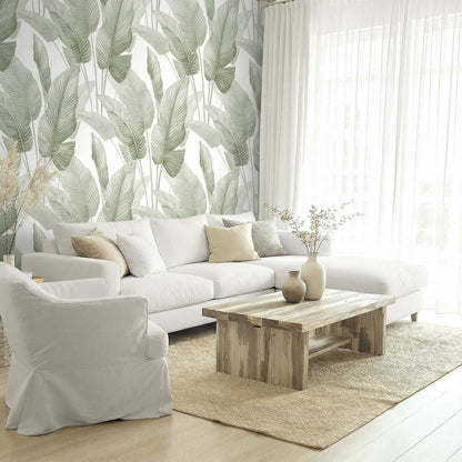 Bright living room with green Lace Leaf Wallpaper, white sofa, armchair, wooden table, and sheer curtains.