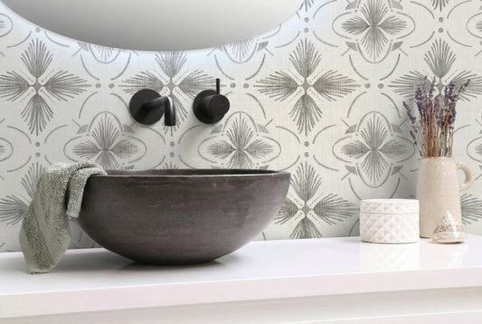 Modern bathroom with a stone sink, gray Tropical Bali Essence Grasscloth wallpaper, towel, and decor on a white countertop.