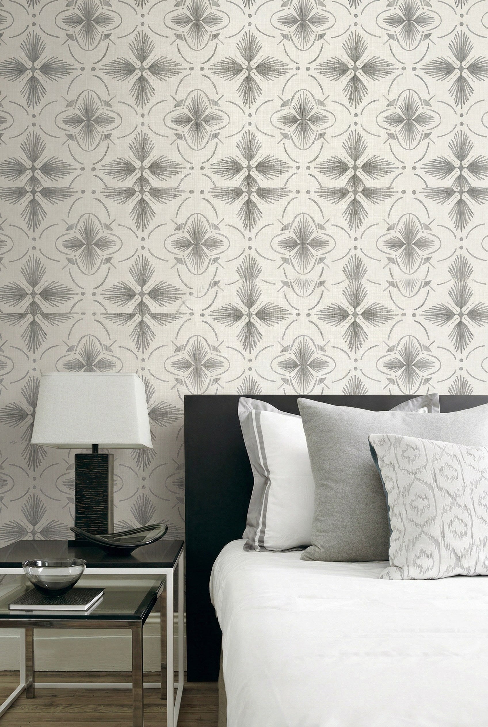 Modern bedroom with a black headboard, gray and white pillows, and Tropical Bali Essence Grasscloth wallpaper.