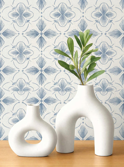 Two white ceramic vases with green leaves on wood, set against Tropical Bali Essence Grasscloth Naturals wallpaper.
