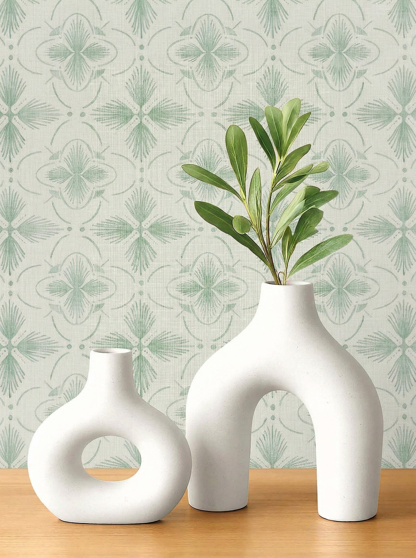 Two modern white vases with green leaves on wood; background: Tropical Bali Essence Grasscloth Naturals in green.