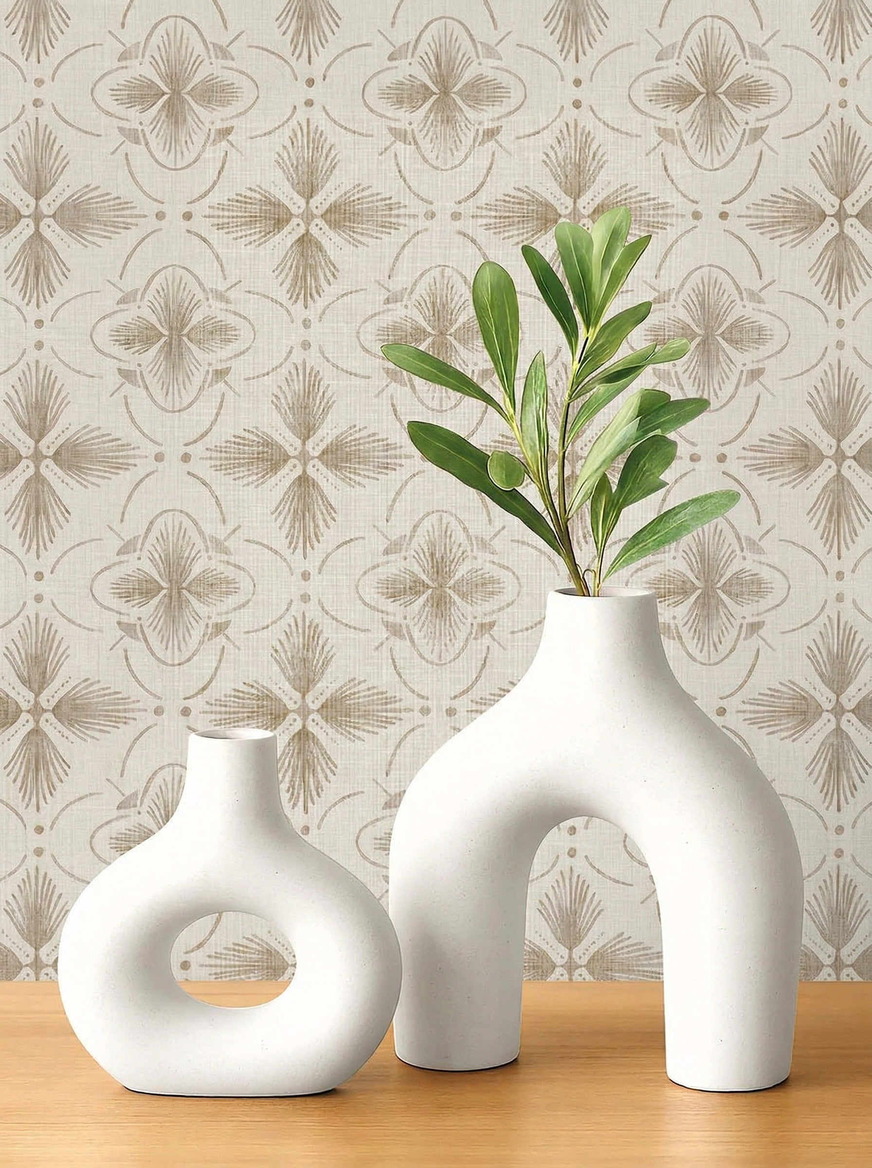 Two modern white vases with green leaves on wood, set before Tropical Bali Essence Grasscloth Naturals wallpaper.