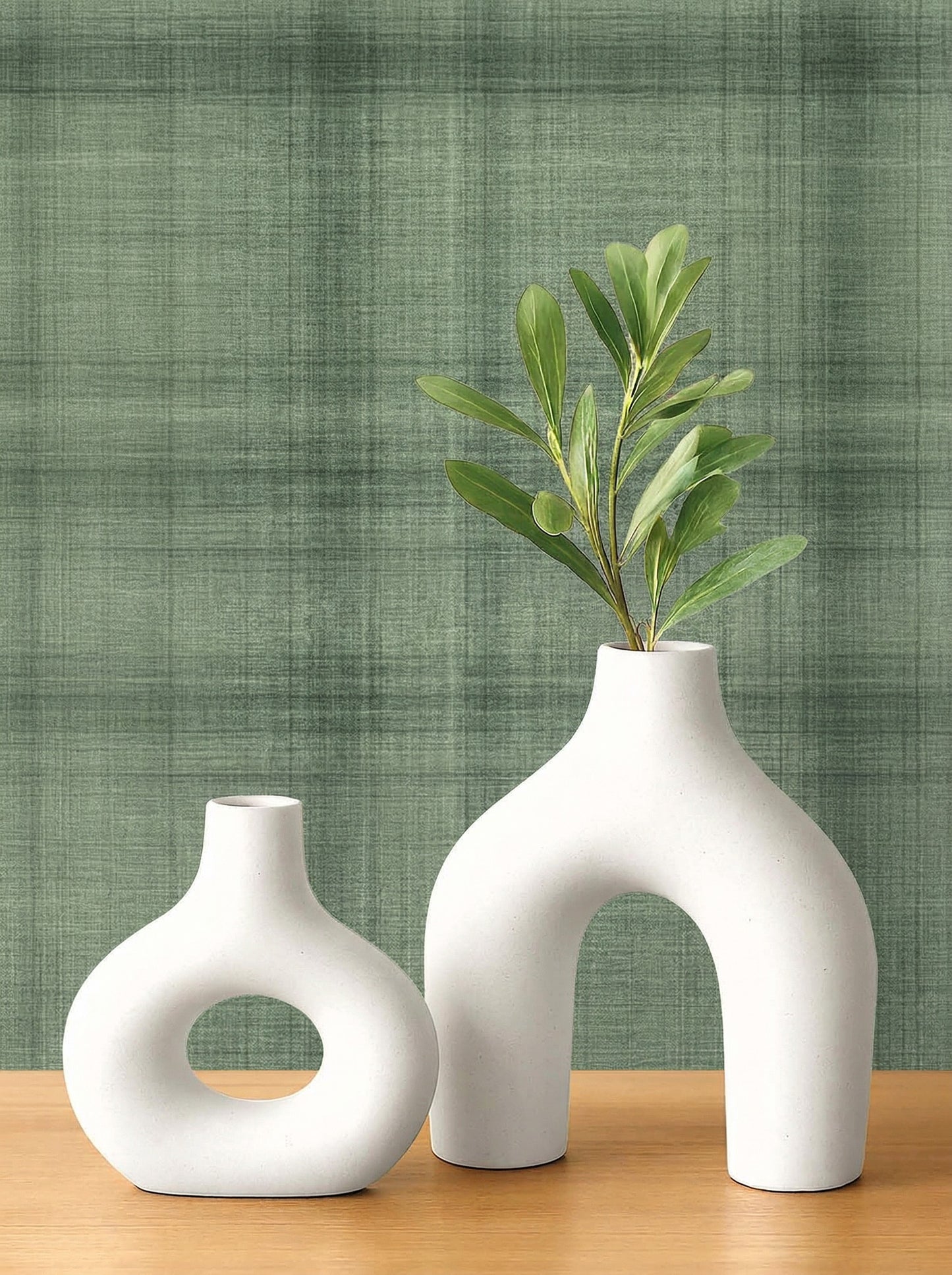 Two white ceramic vases sit on wood, one with green foliage, against a green Textured Plaid Commercial Vinyl backdrop.