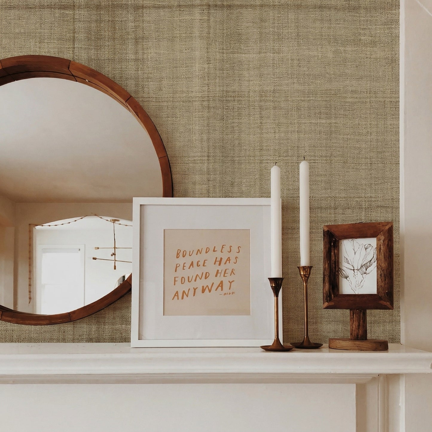 Round mirror, art, tall candlesticks, and branch drawing on a mantel against Textured Plaid Commercial Vinyl wall.