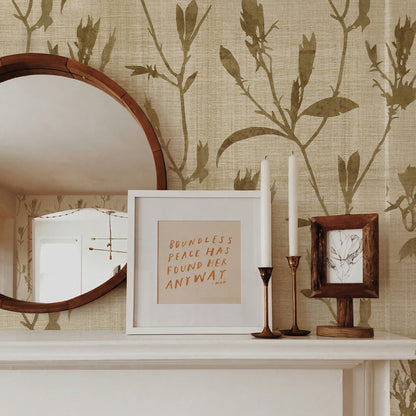 Round mirror, framed quote, candlesticks, and art on a mantel with Botanical Bali Leaf Commercial Vinyl wallpaper.