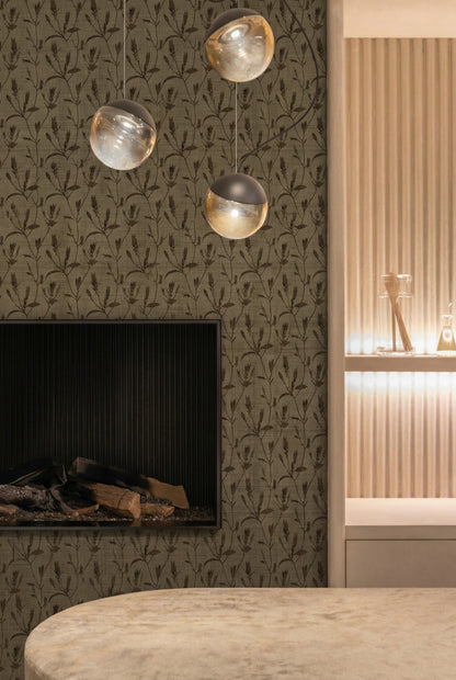Modern interior with Botanical Bali Leaf vinyl wallpaper, three globe pendants, black fireplace, and lit shelf with glassware.