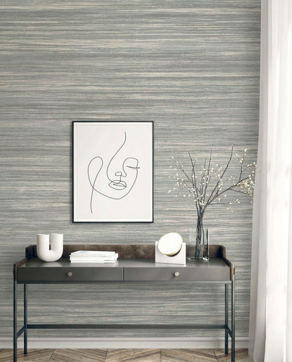 Minimalist console table with decor and abstract face art set against Faux Grasscloth Commercial Vinyl wallpaper.