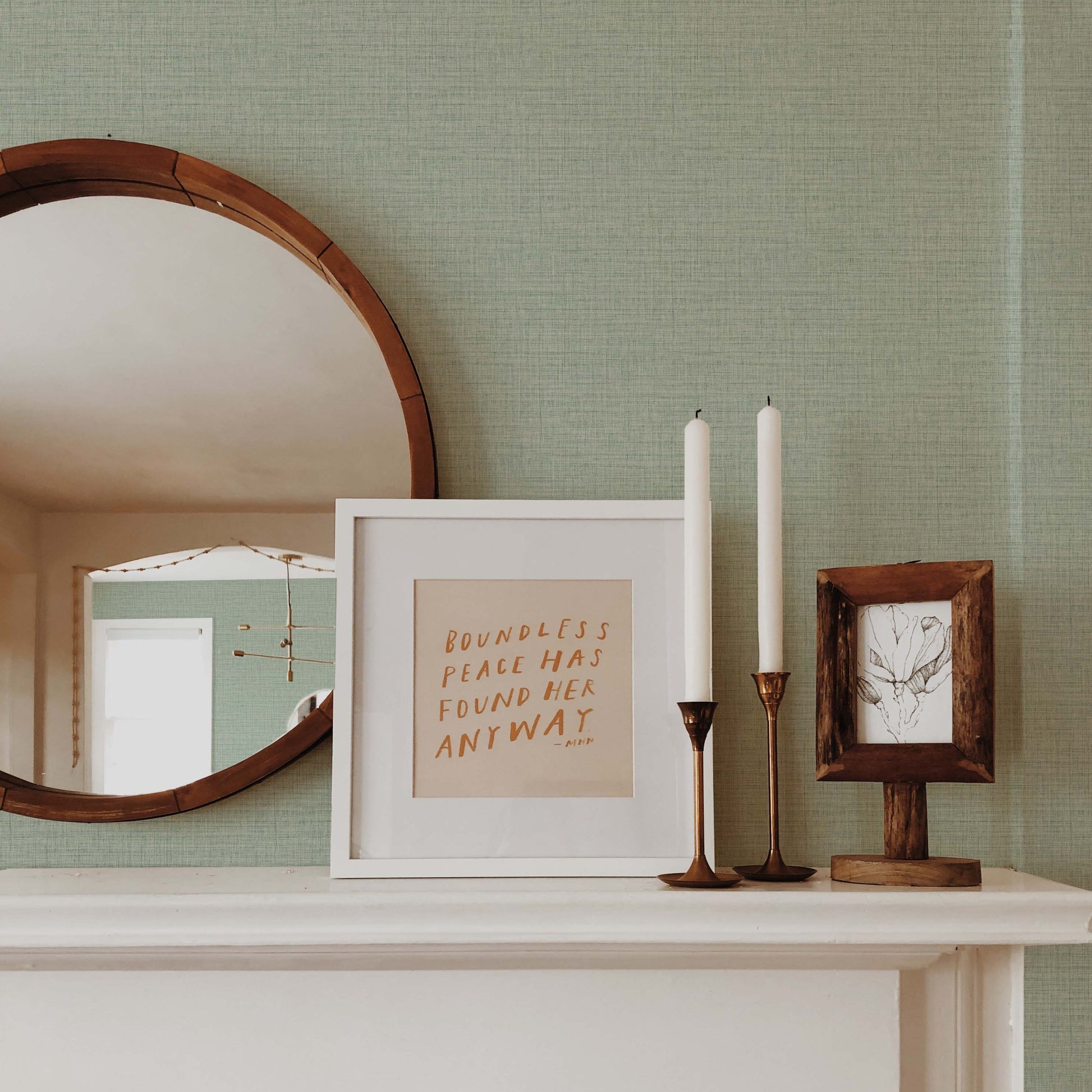 A round mirror, framed quote, and candles stand out on a white mantel against Faux Weave Commercial Vinyl wallpaper.