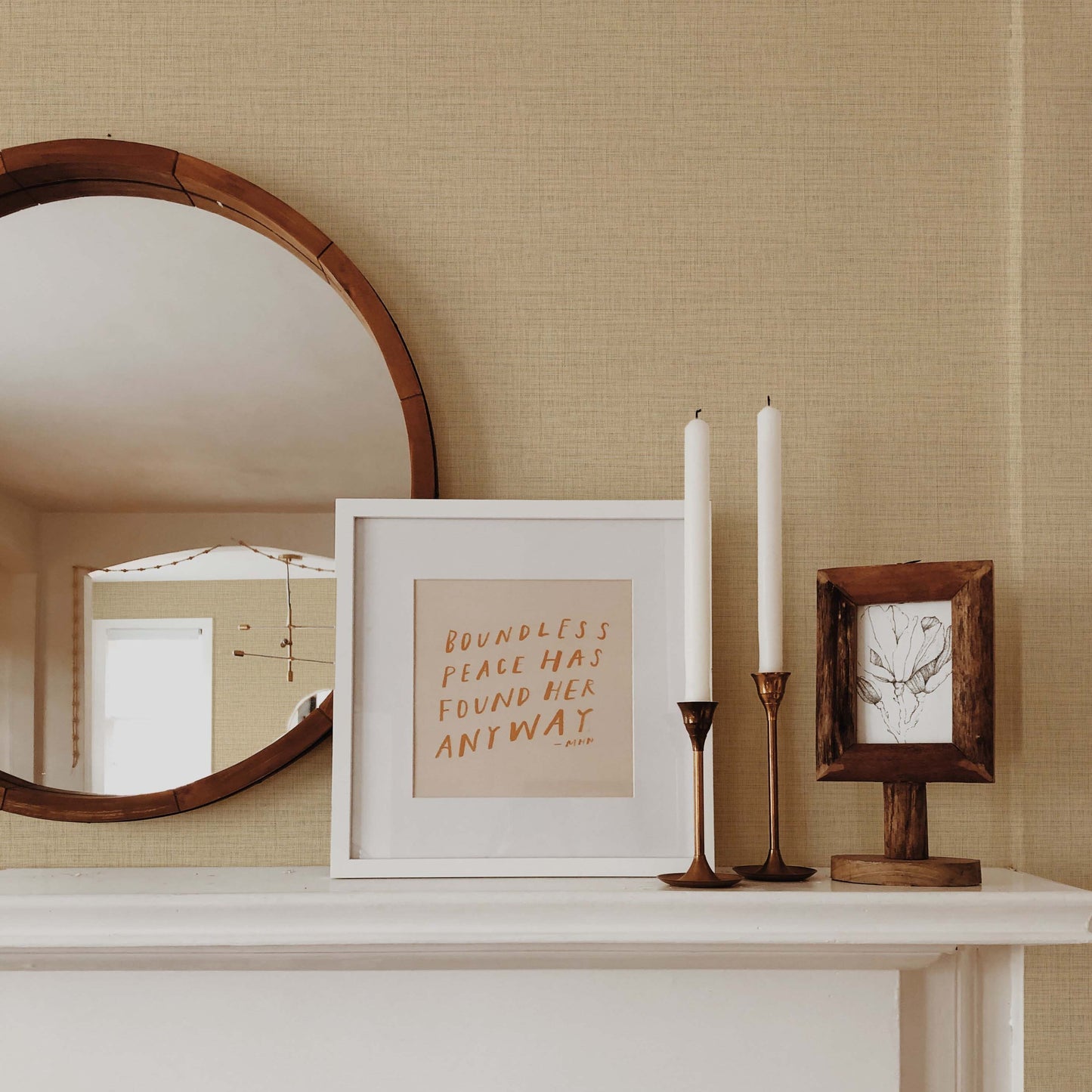 A round mirror, framed art, and candles sit on a white mantel against Faux Weave Commercial Vinyl wallpaper.