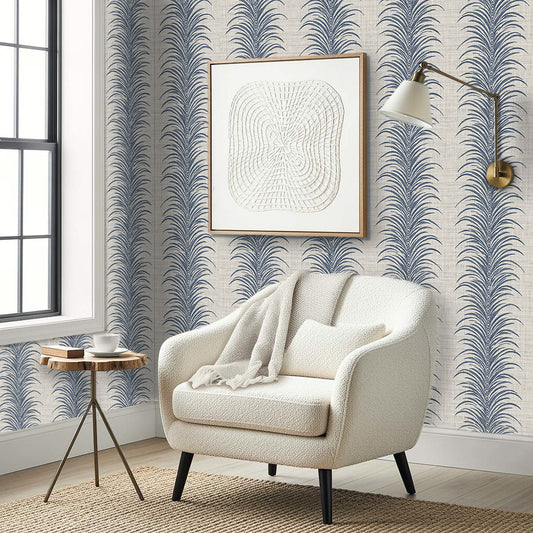 A cozy white armchair with a blanket sits by a table in a modern room with Tropical Bali Leaf Stripe Vinyl wallpaper.