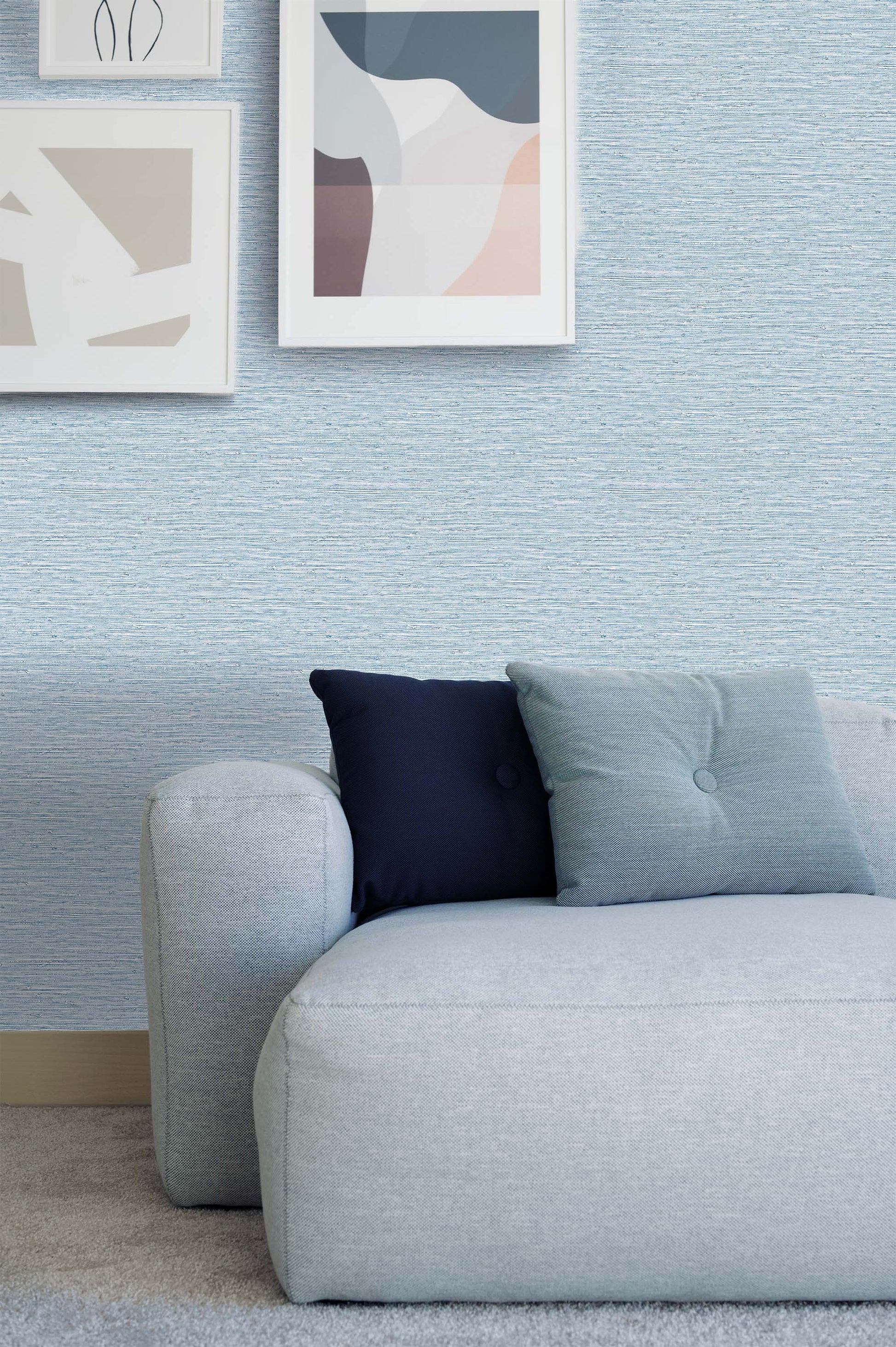 Modern light blue sofa with two pillows, set against Texture Grasscloth Effect Commercial Vinyl wallpaper and abstract art.