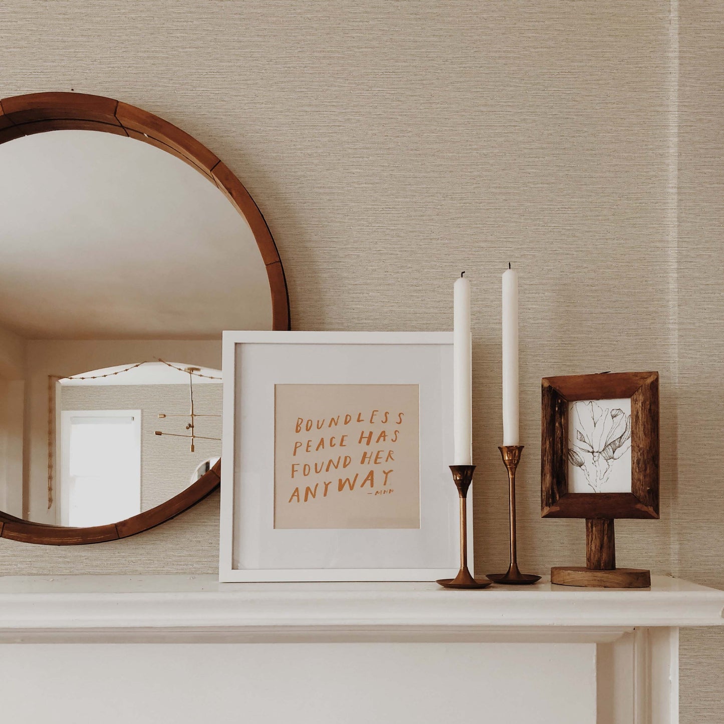 A round mirror, candles, art, and a framed quote decorate a mantel with Texture Grasscloth Effect Commercial Vinyl wallpaper.