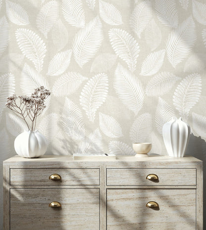 Wooden dresser with decorative vases against a wall decorated with White/Off White Scattered Leaves Wallpaper.
