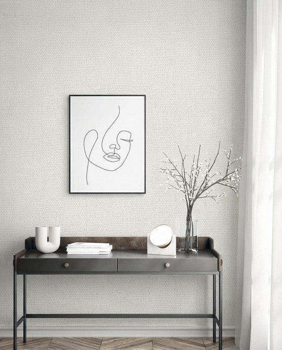 Minimalist room with a black metal console, abstract face art, and Grasscloth Texture Grasscloth Naturals wallpaper.