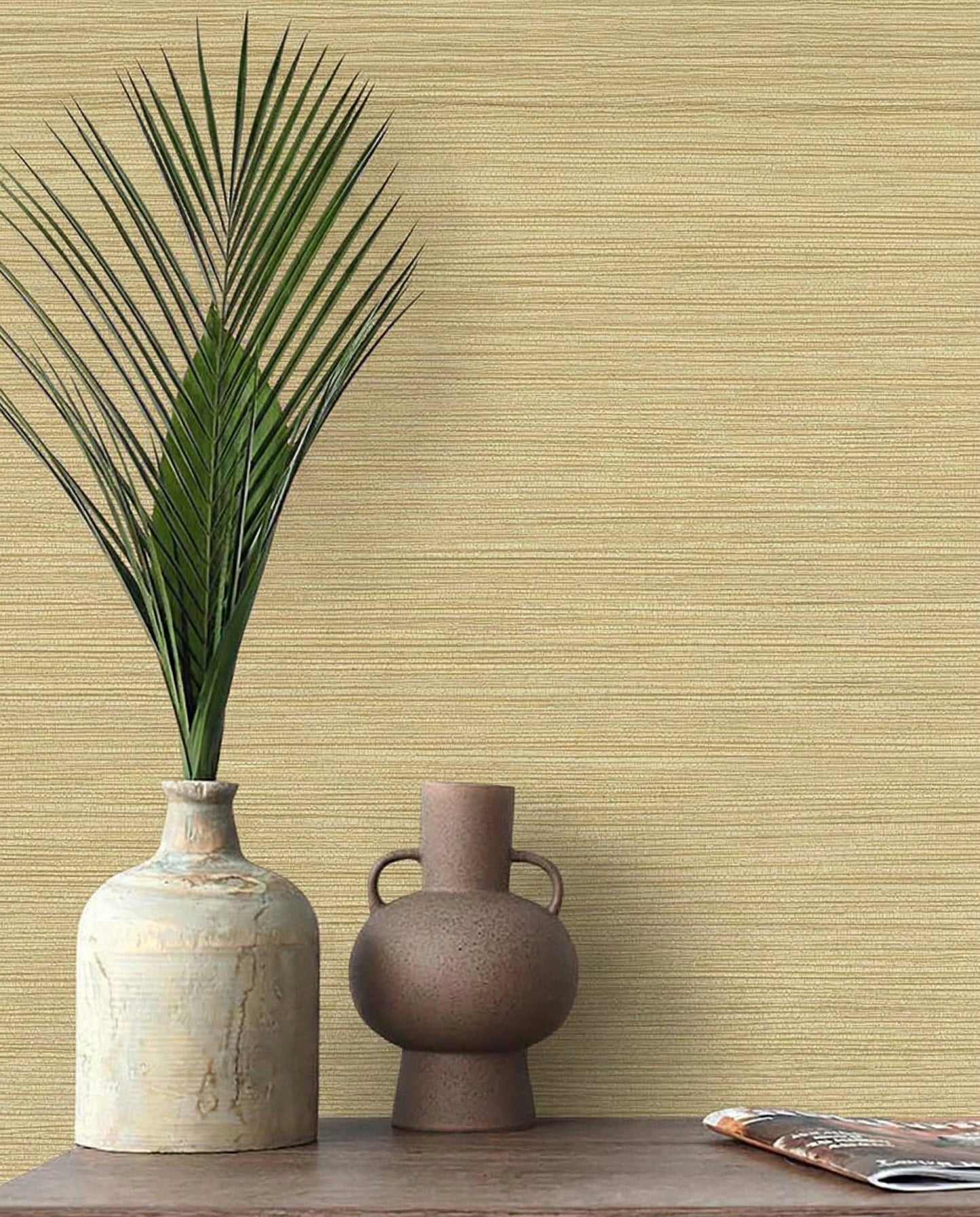 Two ceramic vases, one with a palm leaf, sit on wood against Grasslands Commercial Vinyl wallpaper.