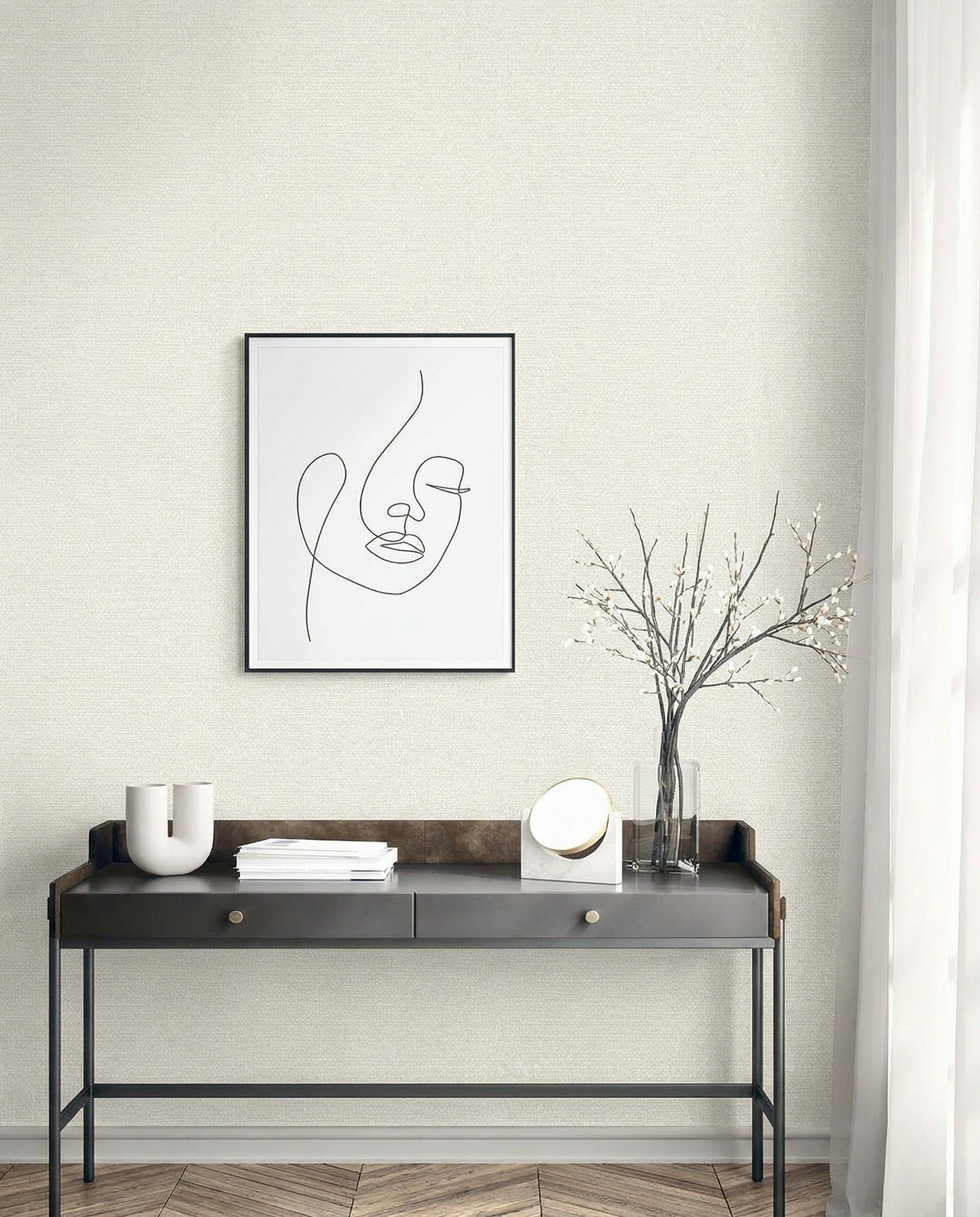Minimalist entryway with a black console, abstract face art, and Natural Raffia Commercial Vinyl wallpaper for neutral style.