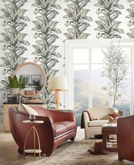 Modern living room with brown leather sofa, beige chairs, Banana Leaf Commercial Vinyl wallpaper, large window, and potted tree.