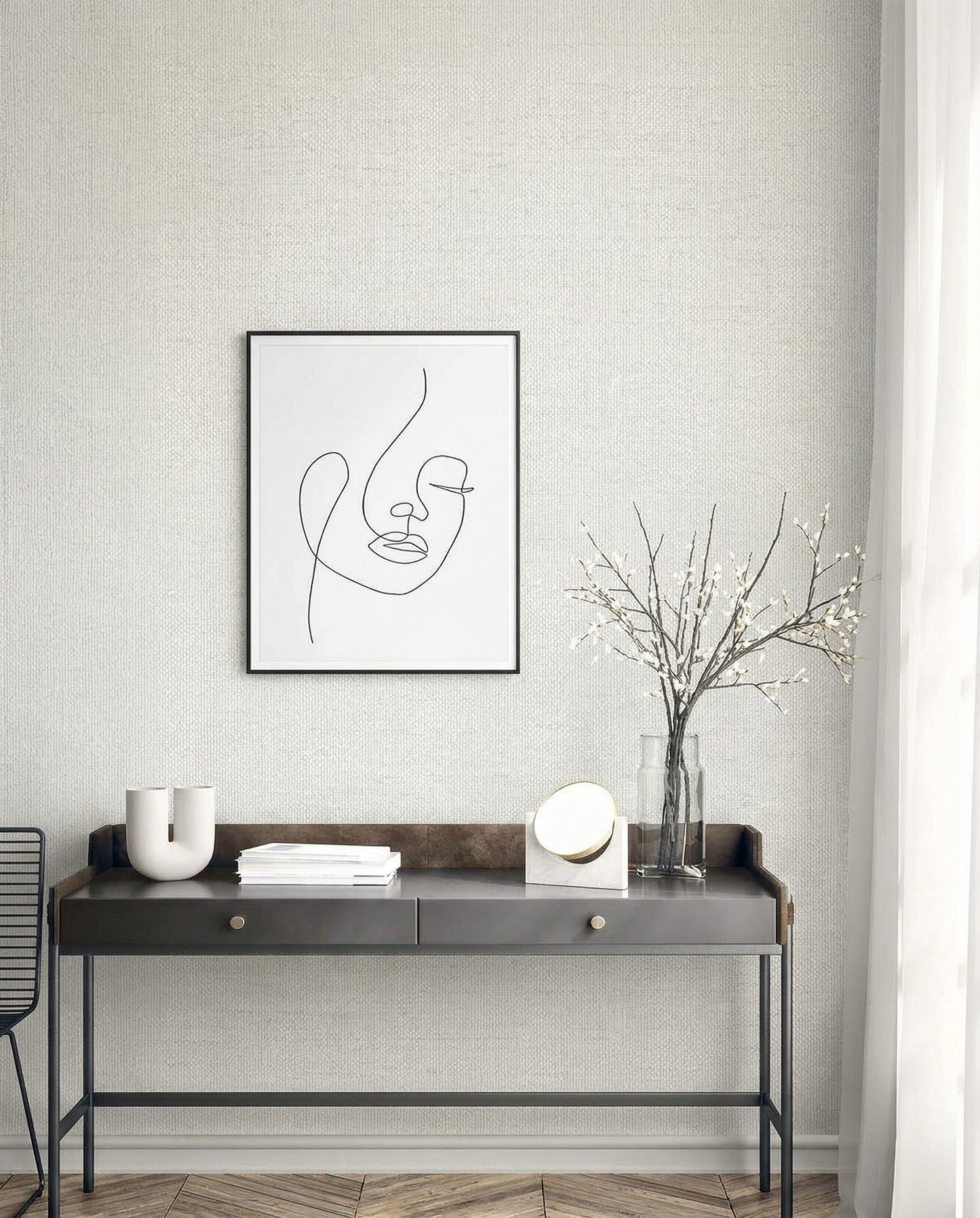 Minimalist desk with decor under a line art portrait on Faux Paperweave Commercial Vinyl wallpaper near sheer curtains.