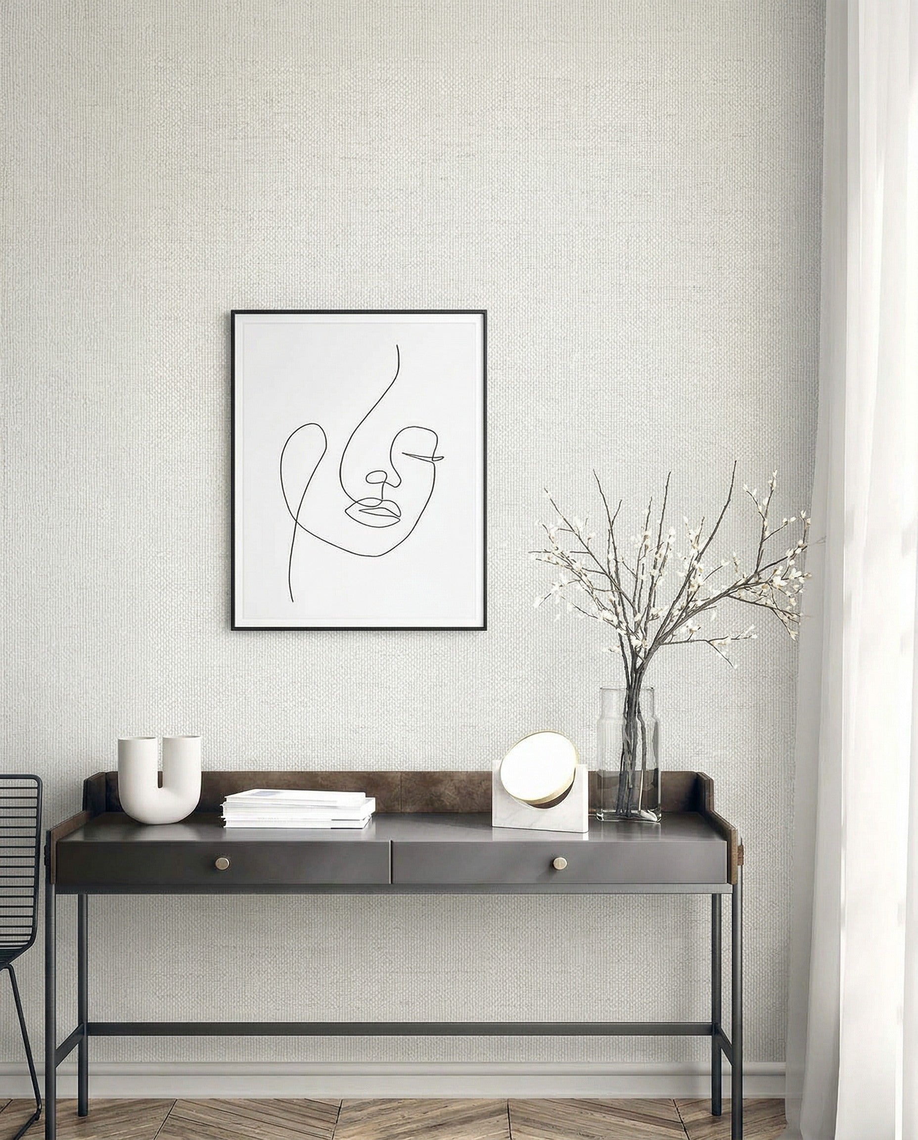 Minimalist desk with decor under a line art portrait on Faux Paperweave Commercial Vinyl wallpaper near sheer curtains.
