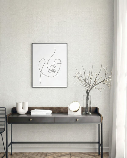 Minimalist desk with decor under a line art portrait on Faux Paperweave Commercial Vinyl wallpaper near sheer curtains.