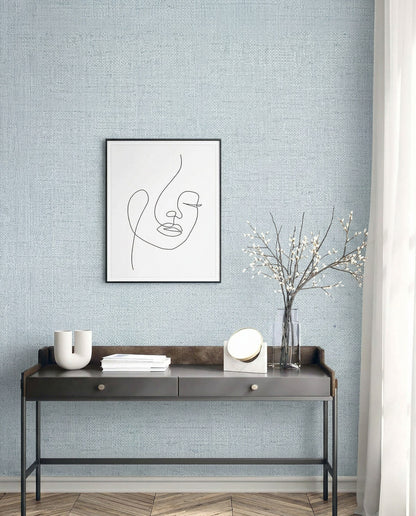 Minimalist desk with decor and art set against Faux Paperweave Commercial Vinyl wallpaper on a light textured wall.