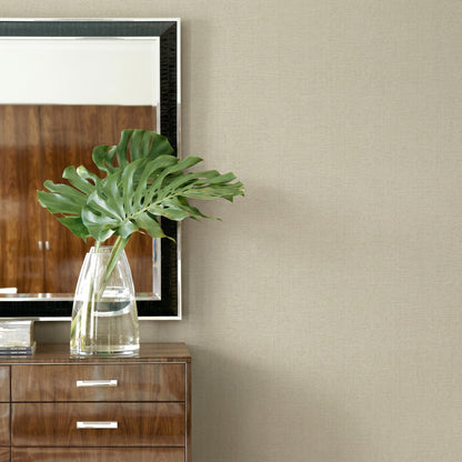 A clear glass vase with green leaves sits on a dresser beneath a mirror and Faux Paperweave Commercial Vinyl wallpaper.