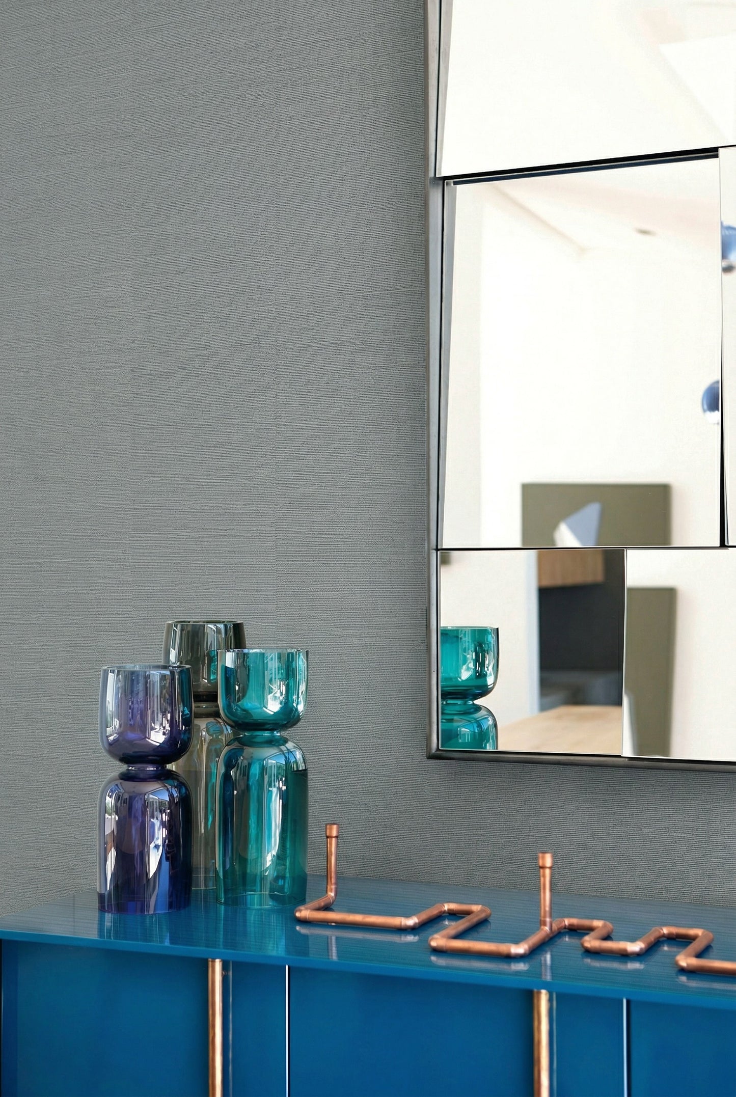 Blue sideboard with glass vases, copper decor, and a geometric mirror on Sisal Texture Grasscloth Naturals.