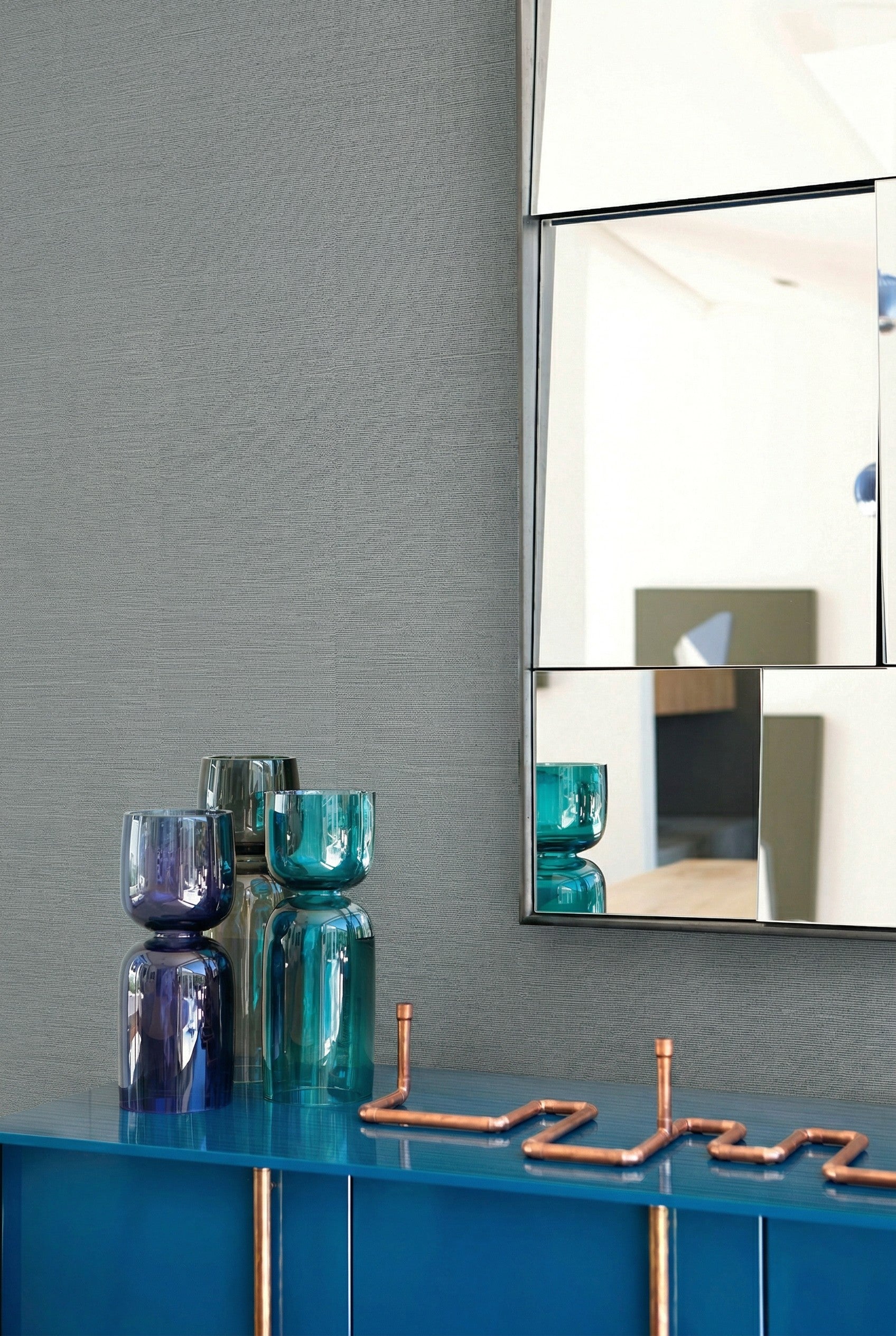 Blue sideboard with glass vases, copper decor, and a geometric mirror on Sisal Texture Grasscloth Naturals.