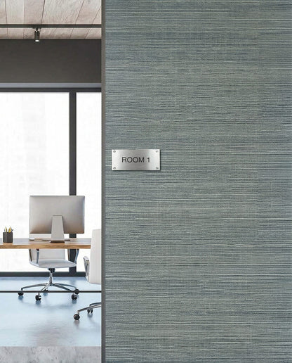 Office room with a ROOM 1 sign on Sisal Texture Grasscloth Naturals wallpaper, desk and chair seen through window.