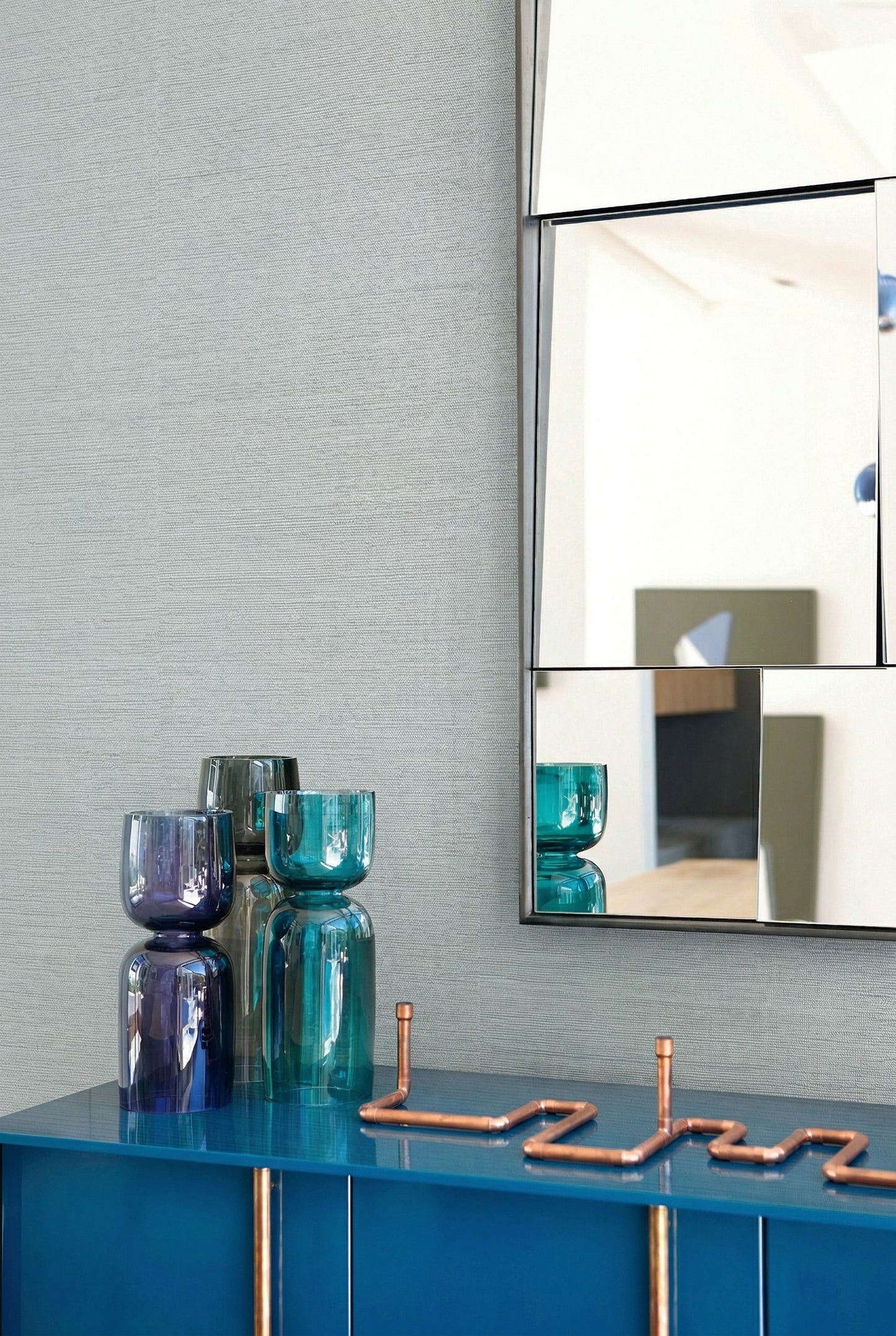 Modern decor with blue glass vases, a geometric mirror, and Sisal Texture Grasscloth Naturals wallpaper.